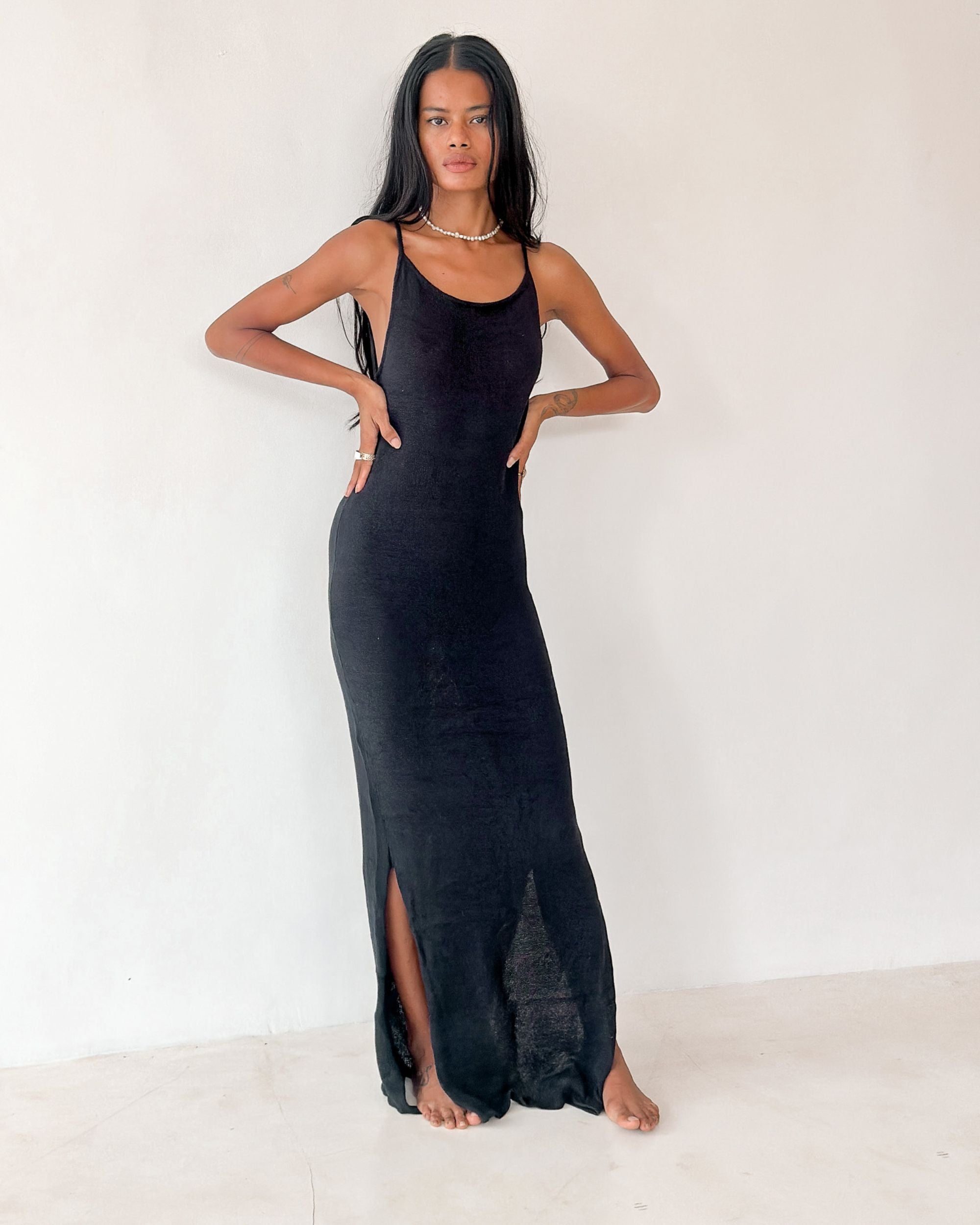 Woman wearing a black slip dress against a white background